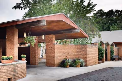 Brick entrance canopy with columns and potted plants at the facility's front exterior.