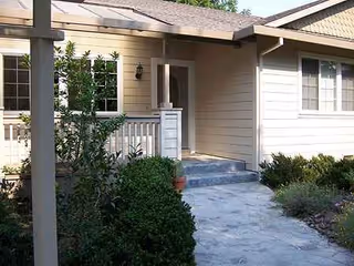 Front entrance of a single-story residential care facility with a walkway and landscaping.