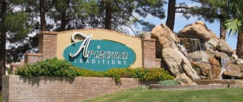 Arizona Traditions sign on brick wall with landscaping and stone waterfall at the entrance