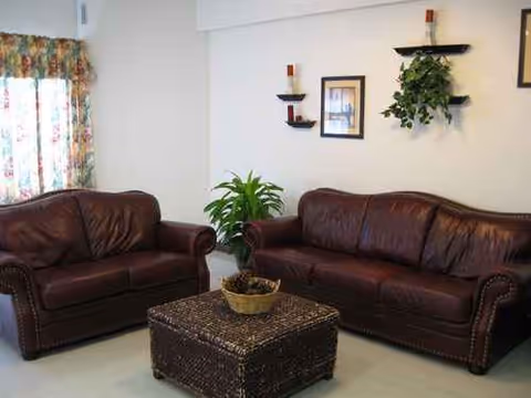 Two brown leather couches surround a woven coffee table in a cozy living room.