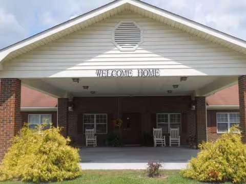Senior living facility entrance with a Welcome Home sign and rocking chairs.