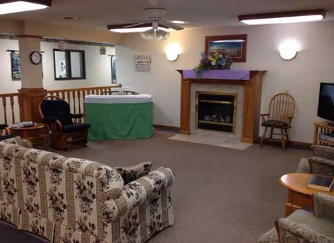 Indoor senior living lounge with floral sofa, fireplace, and comfortable seating.