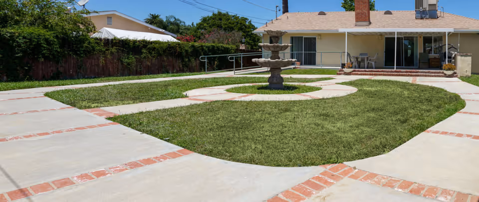 Outdoor courtyard of a senior living facility featuring a central fountain and circular lawn.