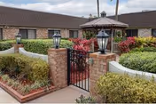 Gated entrance with brick pillars and manicured landscaping at Life Care Center of Altamonte Springs