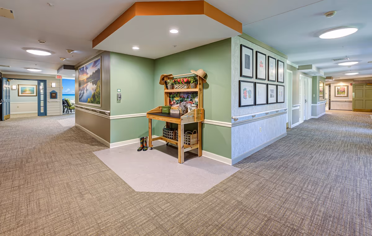 Well-lit interior hallway with green accent walls, framed artwork, and a small wooden display table.