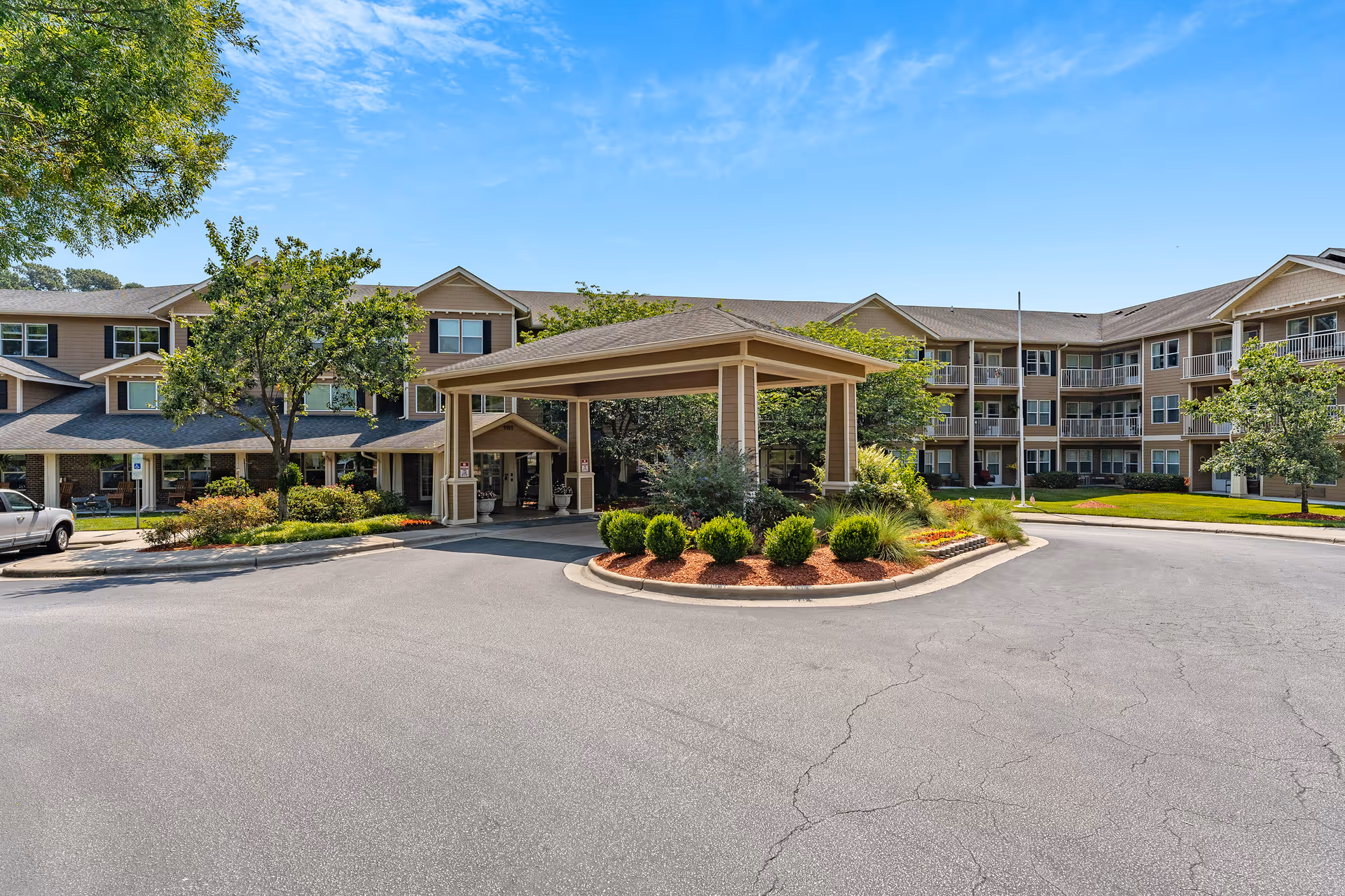 Exterior view of a senior living facility with a covered entrance and circular driveway.