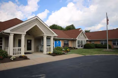 Front view of Altercare Louisville facility with entrance porch, sign, flag, and landscaping.
