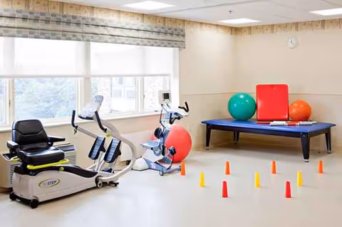 Interior exercise room with stationary bikes, therapy equipment, exercise balls, and cone obstacle course.