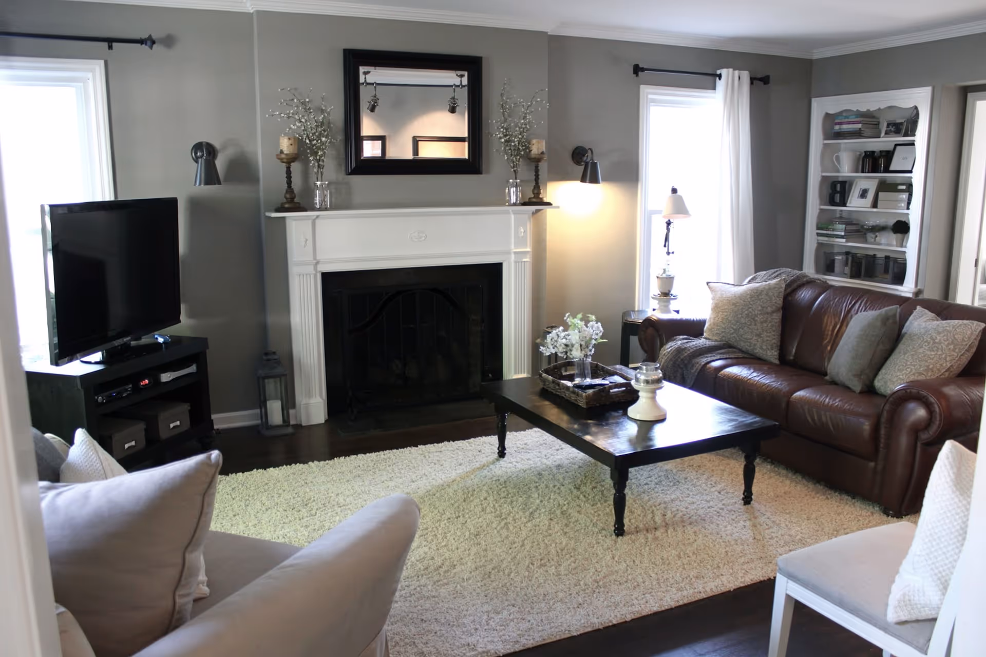 Well-appointed living room with a leather sofa, coffee table, fireplace, TV, and neutral decor.