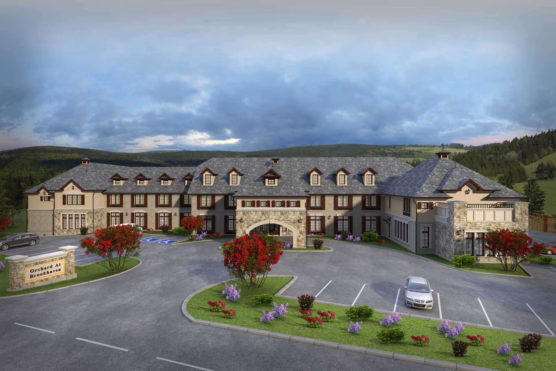 Exterior view of a large, two-story senior living facility named Orchard at Brookhaven, surrounded by landscaped greenery and flowers, with a parking lot in front and hills in the background under a cloudy sky.