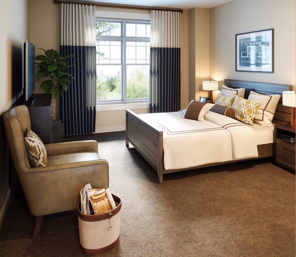 Well-lit furnished bedroom with a bed, armchair, TV, nightstands, and a large window with curtains.