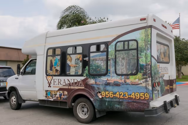 A Veranda Rehabilitation and Healthcare shuttle van with colorful exterior graphics parked outdoors.