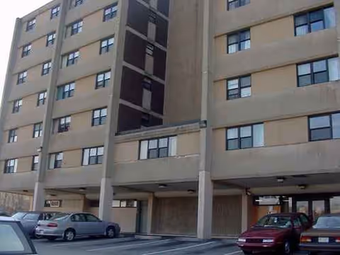 Exterior view of Eastgate Manor, a multi-story senior living building with parked cars.