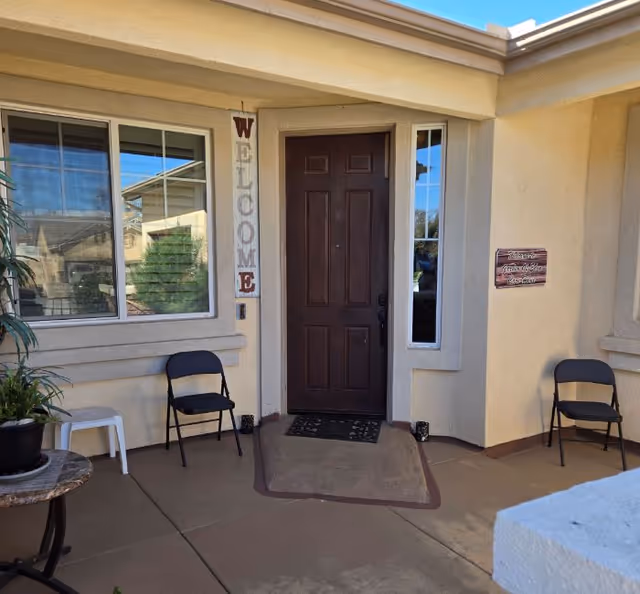 Front entrance of Garden of Eden Care Home with welcome sign, chairs, and porch.