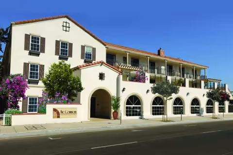 A Mediterranean-style senior living building with arched ground-floor windows and balconies along the front.