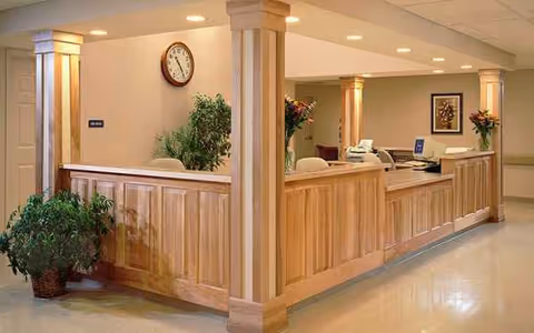 Wood-paneled interior with a curved reception desk, clock, and plants.