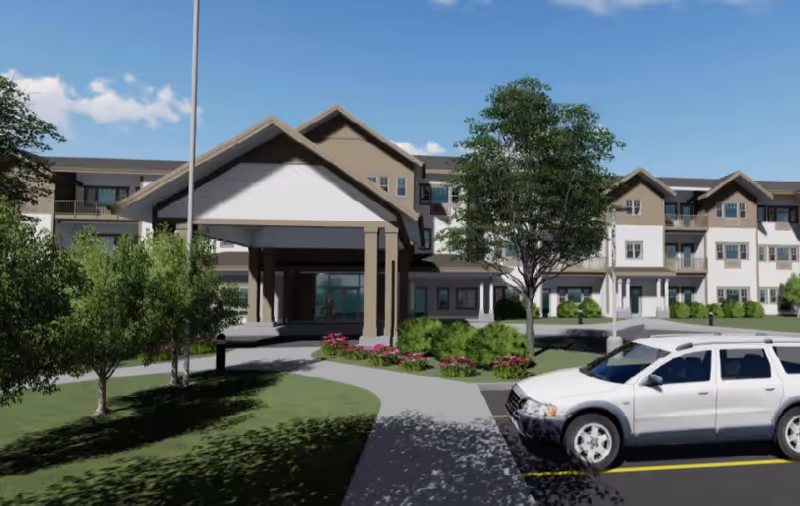 Front exterior of a multi-story senior living building with a covered entrance, landscaping, and a parked white SUV.