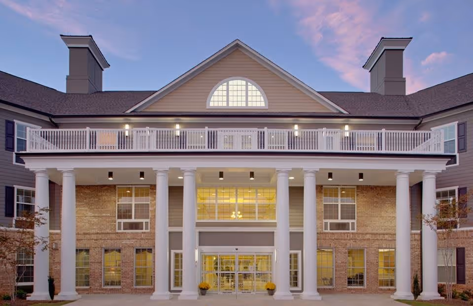 Front exterior view of Canterfield of Oak Ridge building with large white columns, multiple windows, and a balcony under a twilight sky.
