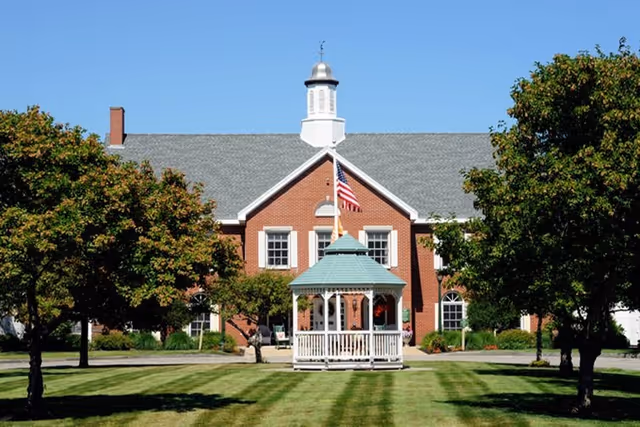 Front view of Huntington Common senior living facility with gazebo and brick facade.