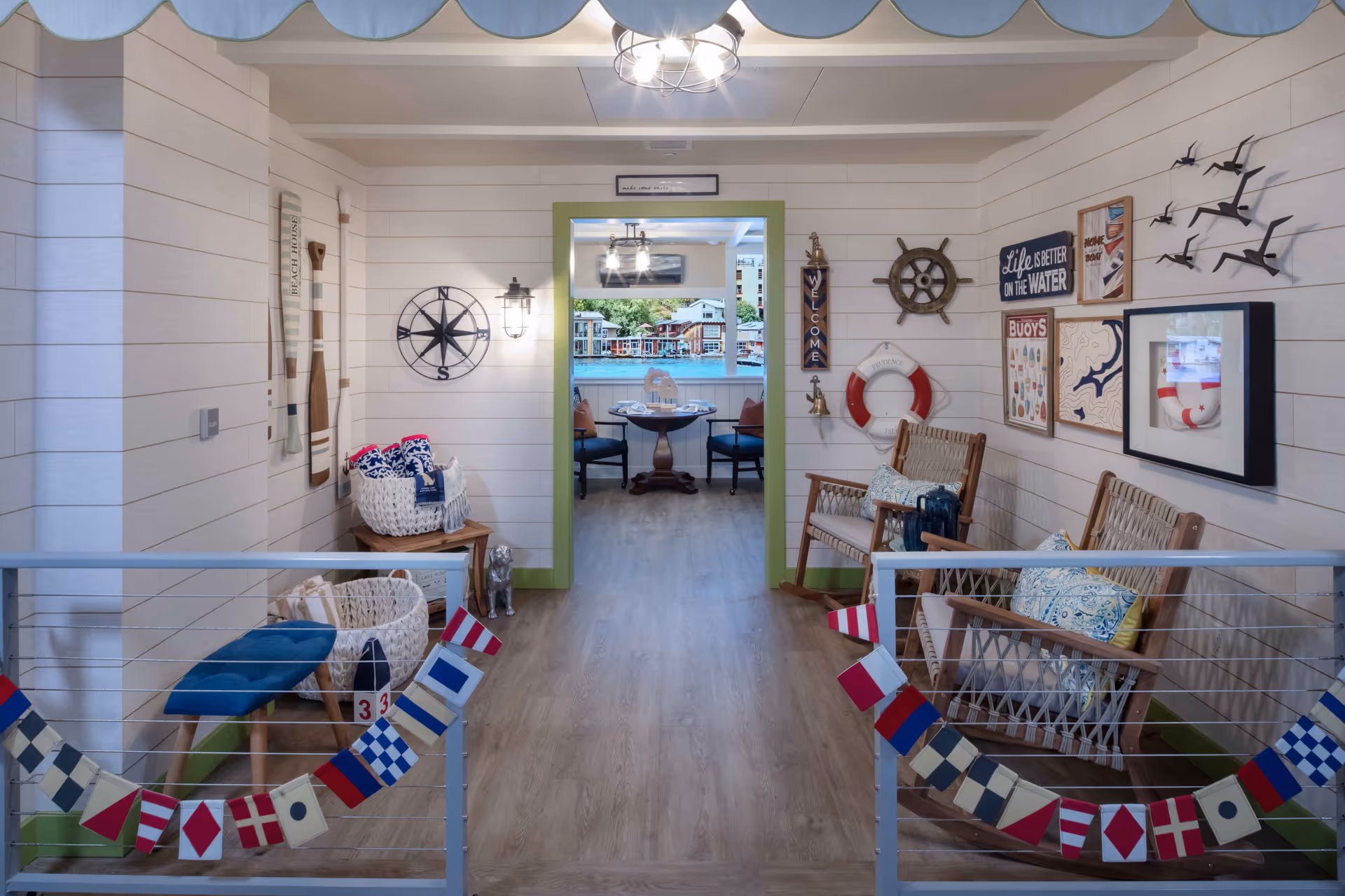 Nautical-themed interior seating area with wicker chairs, coastal wall decor, and a view into a small dining nook.