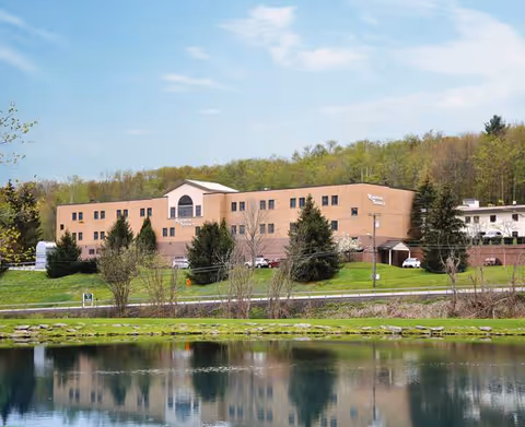Front view of a brick senior living facility beside a calm lake.