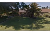 A single-story elder care facility with a large palm tree and well-kept lawn.
