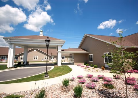 Exterior view of a senior living facility with a covered entrance and landscaped front.