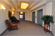 Interior hallway of RiverPointe Senior Community featuring seating, plants, and closed doors.