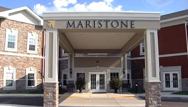 Front entrance of Maristone of Providence senior living facility with columns and seating.