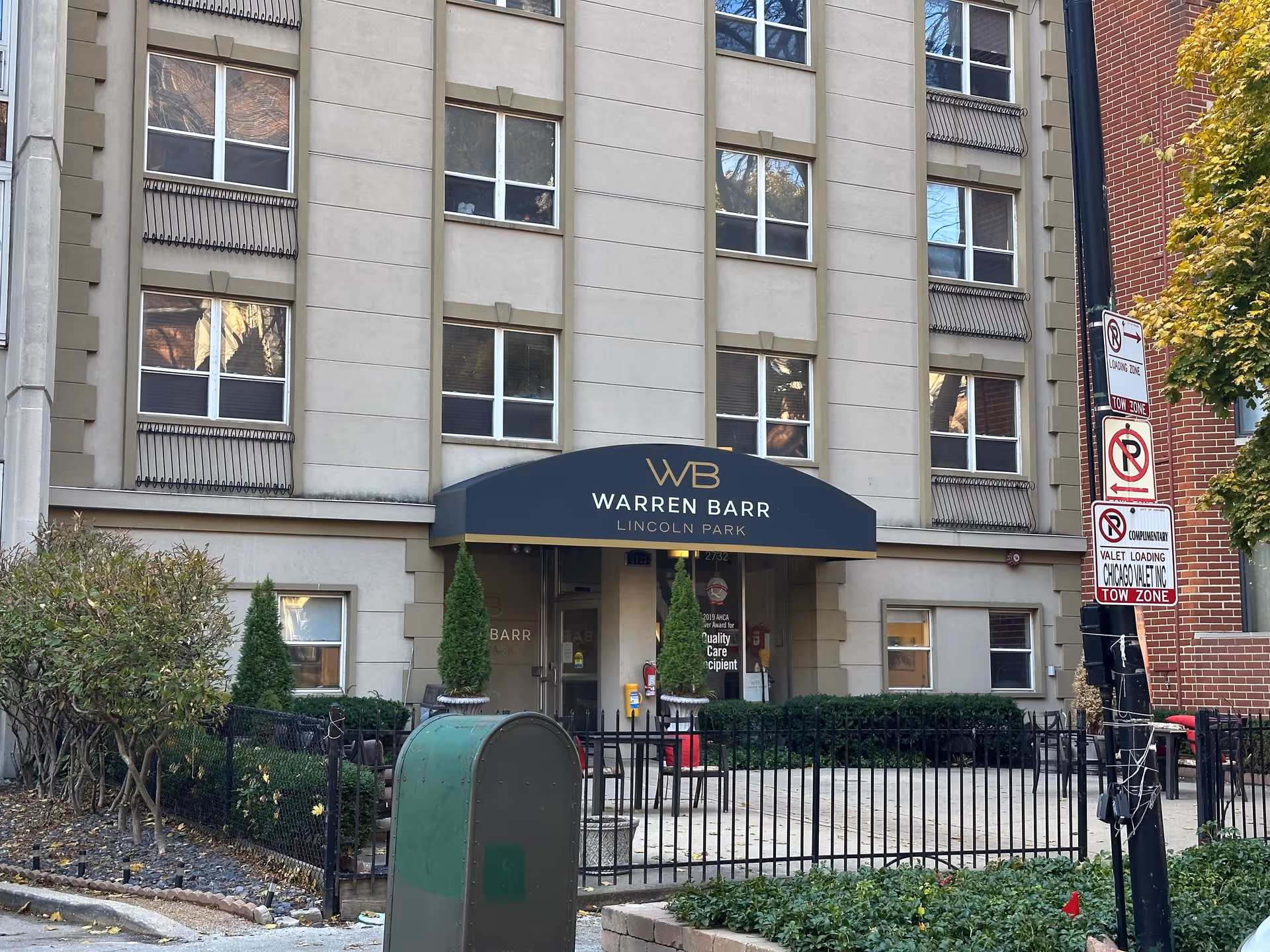 Entrance of the Warren Barr Lincoln Park building with a black canopy bearing the WB logo, windows above, and a small fenced courtyard.