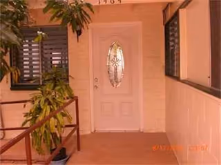 Front entrance of ALFE I Senior Living with a white door and potted plants.