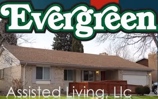 Exterior view of a single-story residential building with a brown roof, beige brick walls, a garage, and a wooden fence in front. The image has the text 'Evergreen Assisted Living, LLC' overlaid at the top and bottom.