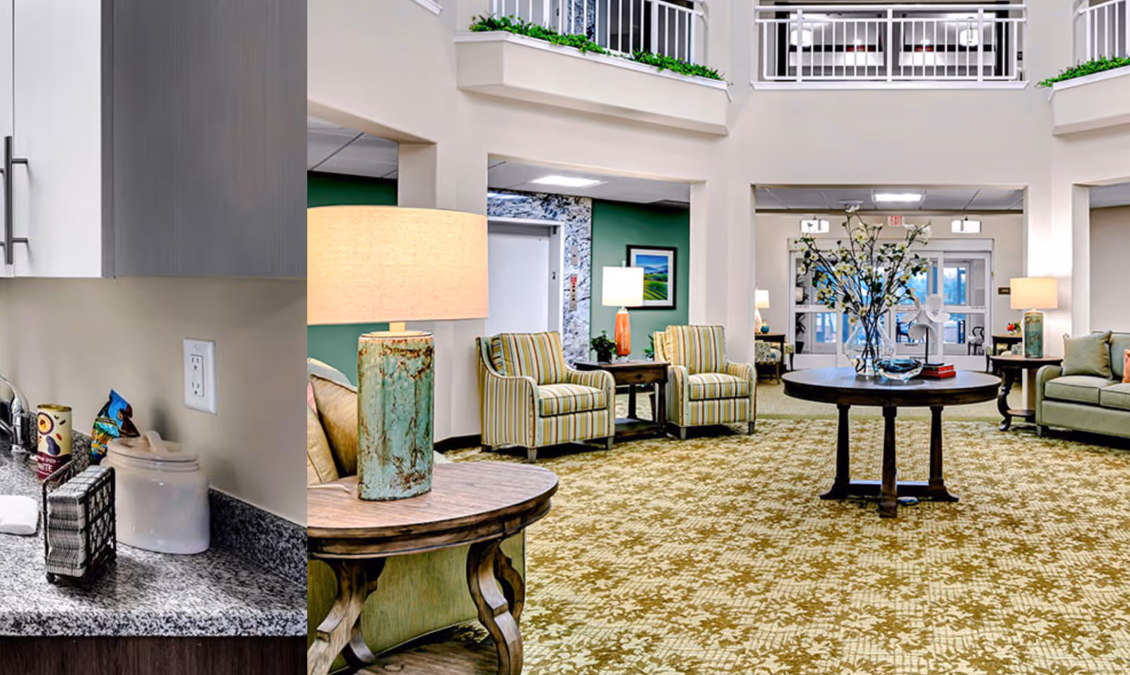A bright and spacious interior common area in a senior living facility featuring a patterned carpet, a round wooden table with a large vase of flowers, several armchairs with striped upholstery, and multiple lamps providing warm lighting. The area has high ceilings with a balcony railing above and an elevator visible in the background.