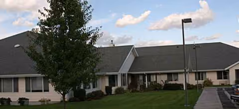 Single-story Avamere at Hermiston exterior with green lawn, tree, and parking.