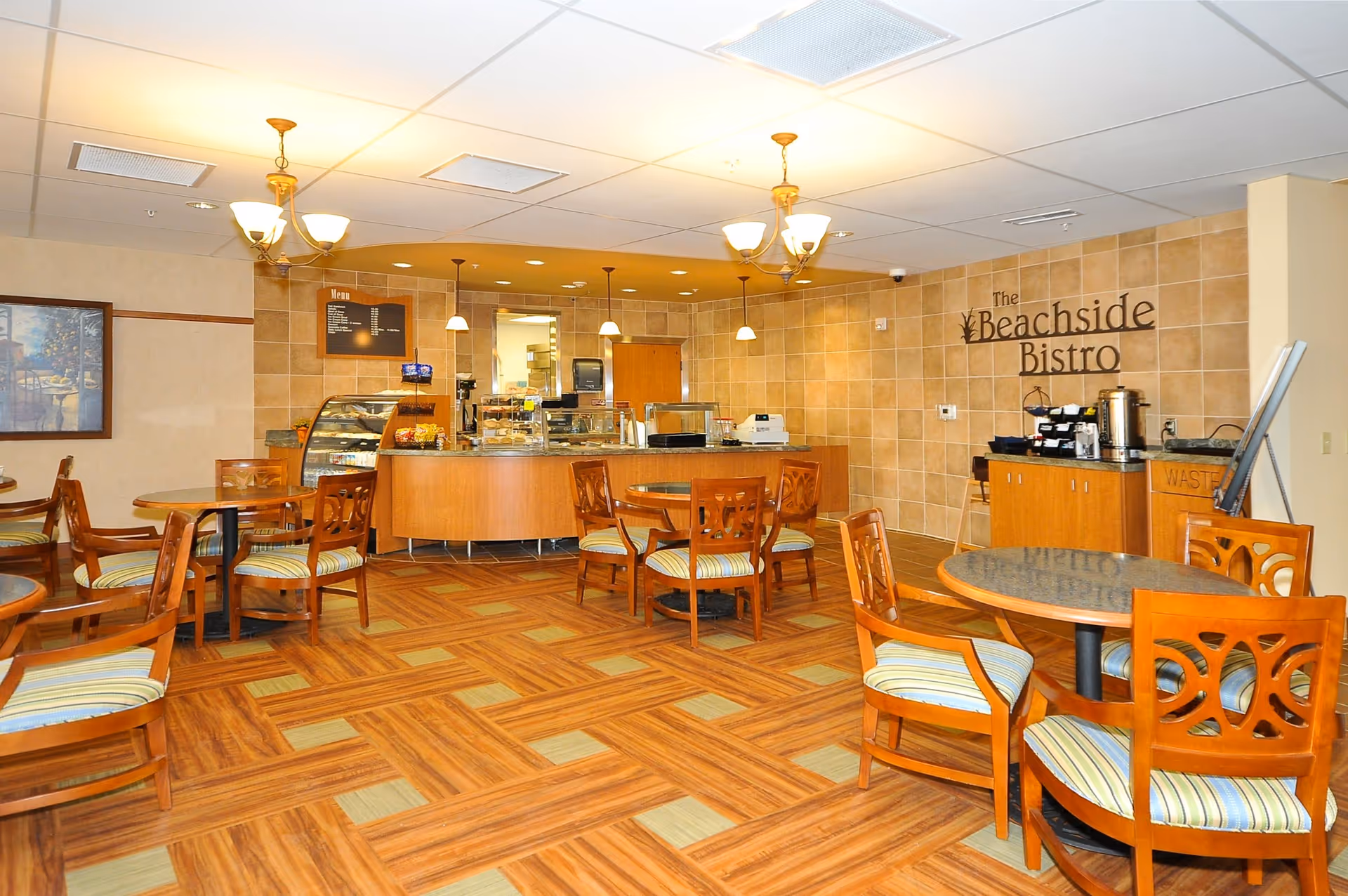 Dining area with wooden tables and chairs facing a service counter labeled 'The Beachside Bistro'.