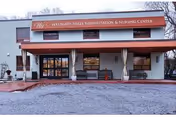 Front exterior view of Westgate Hills Rehabilitation & Nursing Center building with a covered entrance, benches, and a sign displaying the facility name above the entrance.