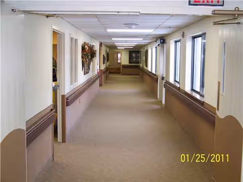 Long hallway inside a senior living facility with doors lining both sides.