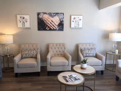 A cozy waiting lounge with three beige tufted chairs, small side tables, and decor.
