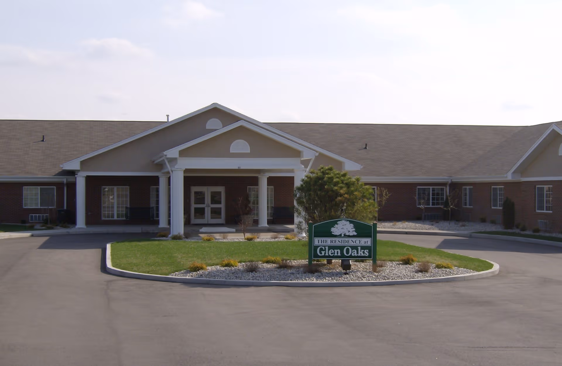 Front entrance of Glen Oaks Health Campus with a covered portico, circular driveway, and a green 'Glen Oaks' sign.
