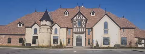 Exterior view of The Highlands at Owasso senior living building with tan stone facade.