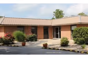 Exterior view of a brick senior living facility entrance with landscaping.