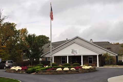 Front entrance of Willow Brook Christian Village with a flagpole, landscaped circular driveway, and a covered portico bearing the facility sign.