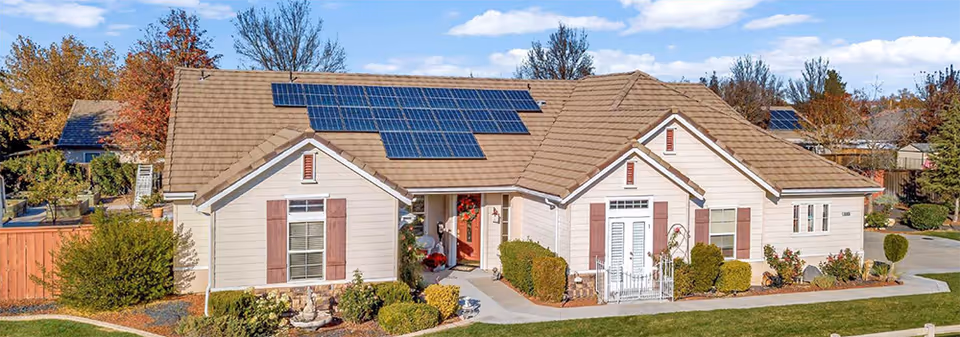 Single-story light-colored senior living building with solar panels on the roof, a central front entrance, and landscaped lawn.