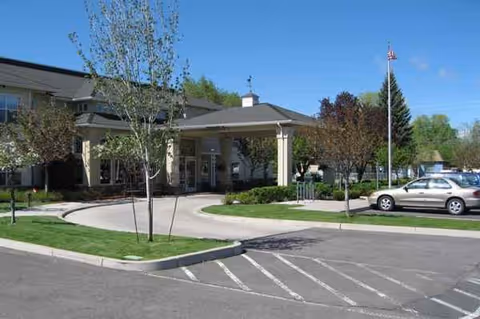 Exterior view of Pelican Pointe by Cogir entrance with curved driveway and parked cars.
