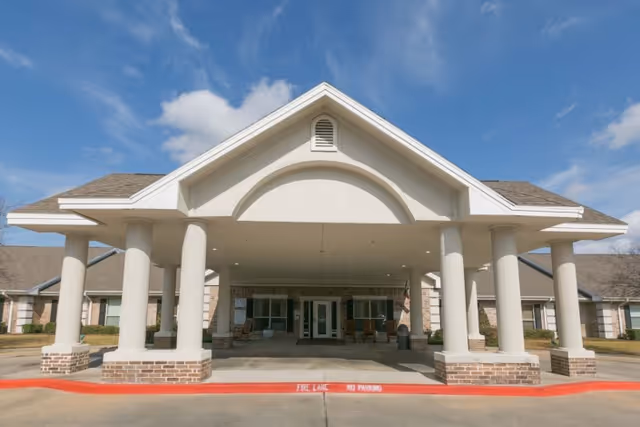 Front entrance of a single-story healthcare building with a covered porte-cochere supported by columns.