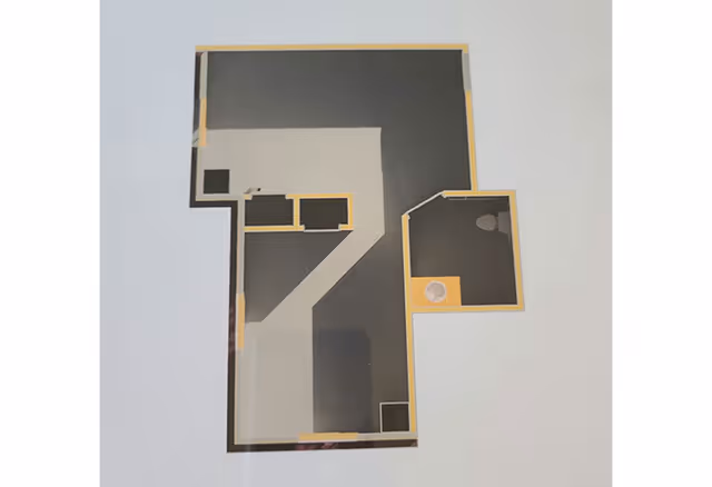 Top-down printed floor plan of a unit with rooms outlined in yellow, showing a small bathroom area with sink and toilet.