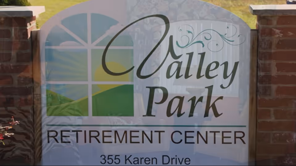 A freestanding sign between brick pillars that reads "Valley Park Retirement Center" with the address "355 Karen Drive."