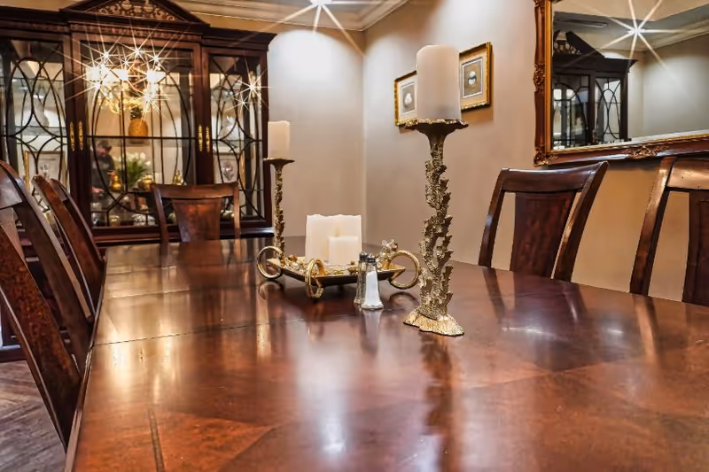 Formal dining room featuring a polished wooden table with decorative candlesticks, chairs, a china cabinet, and a wall mirror.