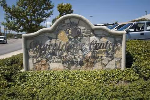 Outdoor stone sign reads 'Regent Care Center' with landscaping and parked cars.