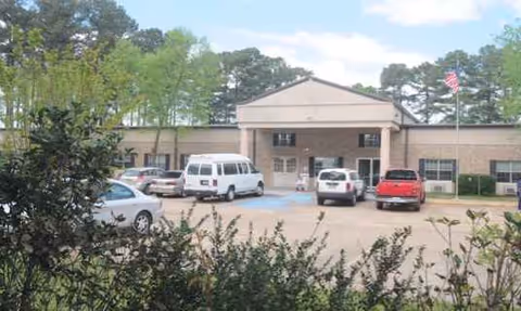 Front view of Ringgold Nurse Care Center with parked cars and trees.